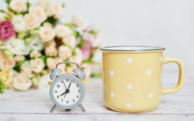 Sıcak bir sabah. Anneler günü çiçek kartı. Bir buket çiçek ve çalar saat. İyi sabahlar. Kadın Günü için yaratıcı bir kahvaltı. Uzayı kopyala Paskalya baharı hayat sahnesi. Kahve kupası. Zaman kavramı.