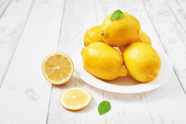 Limonların geçmişi. Beyaz arka planda yaprakları olan bir grup limon. Citruses ve vitaminler. Limon ve yapraklardan oluşan yaratıcı bir düzen. Düz yatıyordu. Yemek konsepti. Vejetaryenlik ve vejetaryenlik. Yaz.