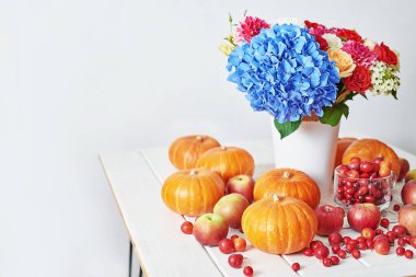 Sonbahar hasat balkabağı arka planı. Balkabakları, elmalar ve çiçekler masada. Şükran Günü masası. Uzayı kopyala Cadılar Bayramı ya da mevsimsel sonbahar. Tasarım modeli. Tebrik kartı. Sonbahar mutfağı