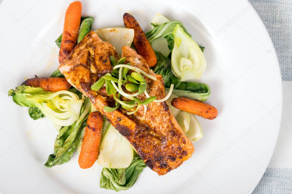 Delicious grilled salmon dish over bokchoy cabbage and roasted baby carrots plate