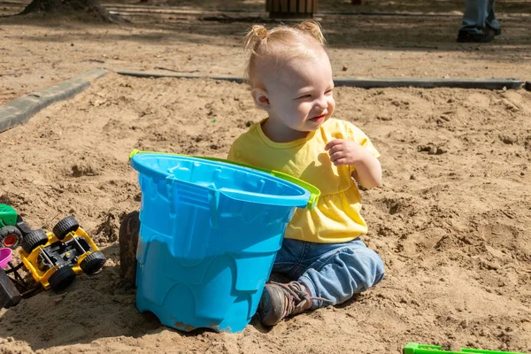 adorable blond caucasian baby playing on sand box