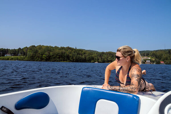 Блондинка-кавказка загорает на палубе лодки
 