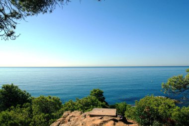 Bir Lloret de Mar, Costa Brava, Katalonya, İspanya Deniz Manzaralı. Yemyeşil ağaçlar ve deniz kenarı taş. Yaz güneşli gün.