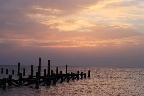 海上的日出 木桩成堆被毁的码头伸出水面 太阳从云层后面探出头来 萨法加 — 图库照片
