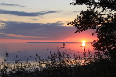 Denizde güzel gün batımı. Gökyüzü parlak renklerle boyanmıştır. Su güneşte yansımasıdır. Yaz gecesi.