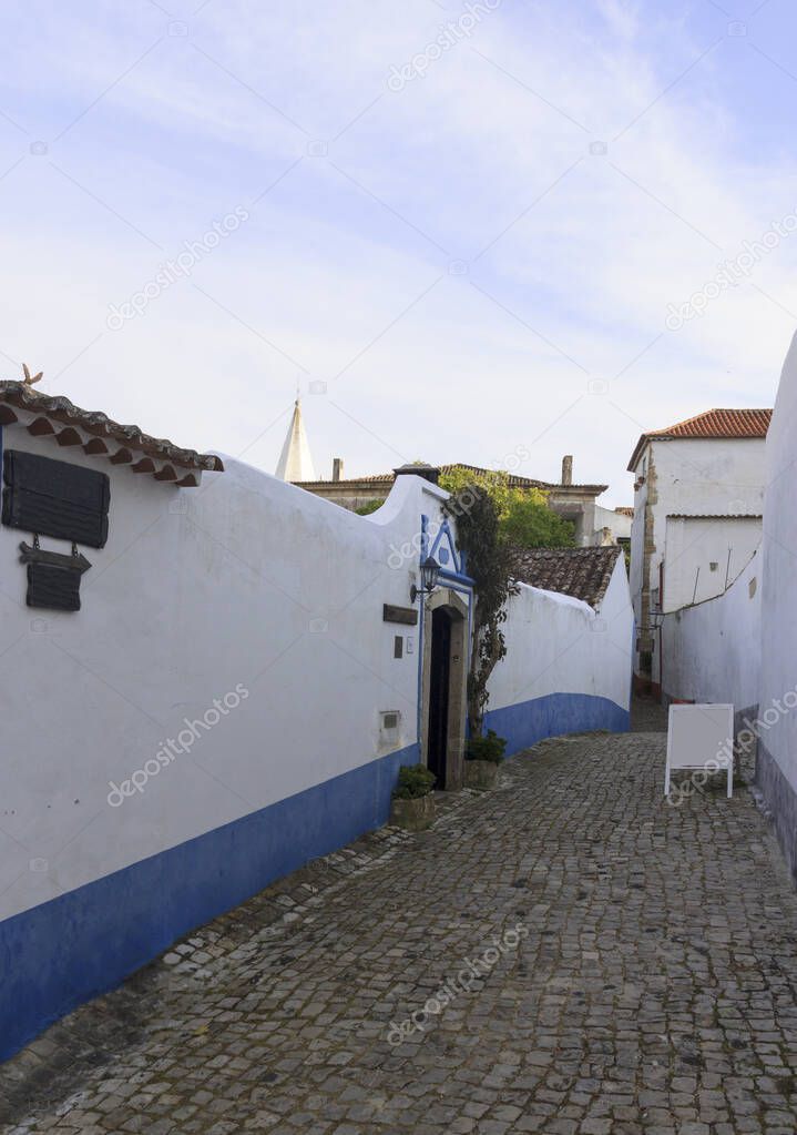 Narrow street of the ancient city of Obidos, Portugal. Scenic ol
