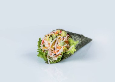 Yengeç etli (yengeç çubukları) Japon Temaki El Suşi, uçan balık yumurtası (Tobiko havyarı), avokado, salata yaprağı, pirinç, Norveç yosununda susam tohumu. Yakın plan Pan Asya menüsü. Boşluğu kopyala.