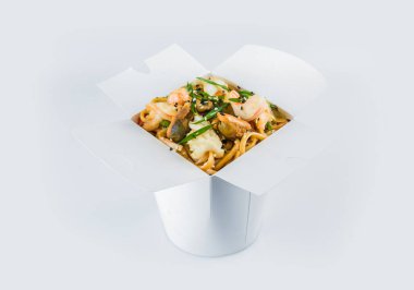 İçinde hazır yemekler olan tecrit edilmiş yemek kutusu. Karides, midye, kalamar, istiridye, sebze ve taze soğan soğanlı Asya deniz ürünleri Udon Noodles beyaz karton paket paket.