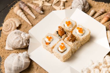 Asya 'nın geleneksel Ebi Tempura Sushi' sinin deniz kabuklarıyla birlikte kum arka planında servis kutusunda yan görüntüsü. Siyah kaplan karidesi, susam tohumu, Japon mayonezi ve kırmızı havyarla yuvarlan..