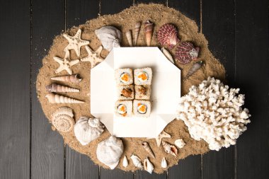 Asya 'nın geleneksel Ebi Tempura Sushi' sinin deniz kabuklarıyla birlikte kum arka planında servis kutusunda en üst görüntüsü. Siyah kaplan karidesi, susam tohumu ve ahşap zemin üzerinde kırmızı havyar ile Japon Roll.