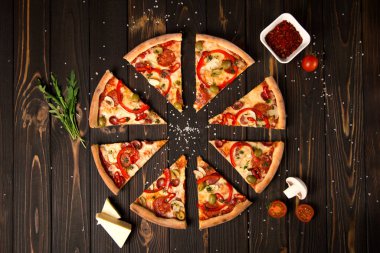 Biberli dilimlenmiş pizza, yeşil zeytin, sosis, mozzarella peyniri, pepperoni, salam, kırmızı biber, ahşap arka planda şampiyonlar. Lezzetli pizza parçaları. Fast food lezzetli yemekler.