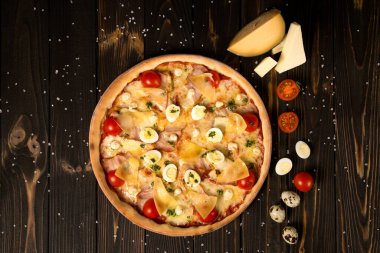 Kiraz domatesli pizza, pesto sosu, parmesan peyniri, tavuk filetosu, domuz pastırması, bıldırcın yumurtası, ahşap zemin üzerinde mozzarella peyniri ve deniz tuzu ve malzemesi. Lezzetli kesilmemiş pizza.