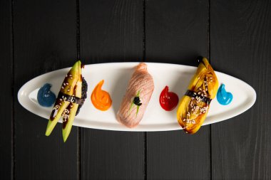 Japon Nigiri Sake Suşi seti somon Tataki ile Nigiri yakınlarında avokado ve Tamagoyaki omletli. Yemek süsleri beyaz tabakta boyanıyor. Pan Asya restoranının menüsü ahşap tahtada üst görünüm