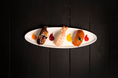 Japon Nigiri Sake Suşi, Nigiri Ebi yakınlarında kaplan karidesli ve yılan balıklı Unagi. Tabakta renkli yemek süsleri var. Tahta üzerinde Asya restoranı menüsü üst görünümü.