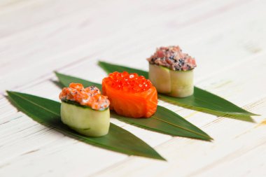 Japon Gunkan Maki Suşi Rolls: Somon havyarlı sake, salatalıklı ton balığı ve bambu yapraklı somon balığı. Pan Asya yemekleri. Pahalı deniz ürünleri lokantası manzarası.