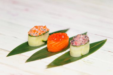 Bir set Japon Gunkan Maki Suşi Rolls. Sake nigiri ve somon ve tobiko roe. Somon havyarlı Gunkan. Salatalıklı Maguro ve ton balığı ve uçan balık yumurtası. Yeşil bambu yapraklarıyla servis edilir..