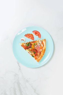 Maydanozlu etli pizza. Domatesli tabak, salam, jambon, şampiyonlar ve Mozzarella peyniri. Pastel turkuaz servis tabağındaki malzemeler. Beyaz mermer zemin üzerinde mavi tablo takımı.