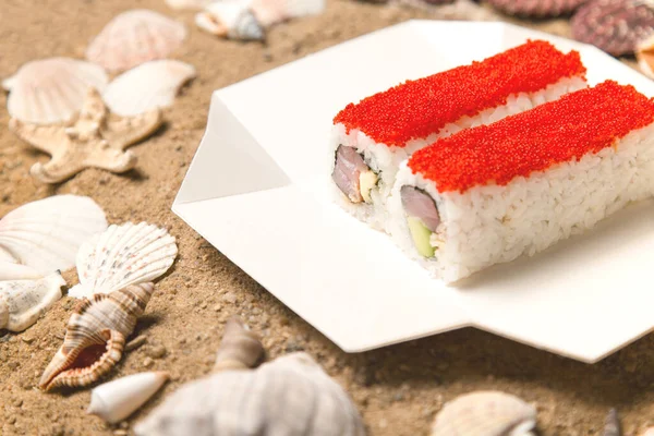 Japon suşisi paket servis kutusunda. Ton balığı, avakado, deniz yosunu ve deniz kabuğu ve yıldızlı kumla kaplanmış pirinç. Üzerinde kırmızı uçan balık yumurtası (Tobiko havyarı) olan Asya yemeği.. 