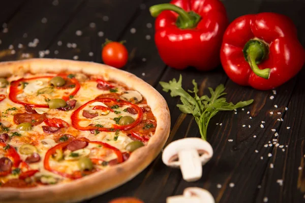 Pizzanın bir kısmı dolmalık biber, şampiyonlar, kiraz domatesleri ve tahta arka planda bitkiler. Kesilmemiş pizzaya yaklaş