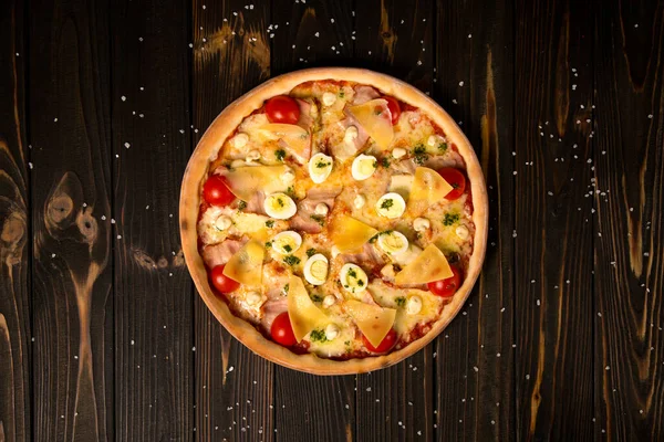 Çeri domatesli geleneksel İtalyan pizzası, pesto sosu, parmesan peyniri, tavuk filetosu, domuz pastırması, bıldırcın yumurtası ahşap zeminde mozzarella peyniri. Lezzetli kesilmemiş pizza.