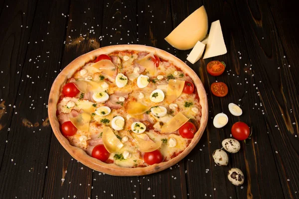 Kiraz domatesli pizza, pesto sosu, parmesan peyniri, tavuk filetosu, domuz pastırması, bıldırcın yumurtası, ahşap zemin üzerinde mozzarella peyniri deniz tuzu ve malzemeleriyle. Lezzetli kesilmemiş pizza.