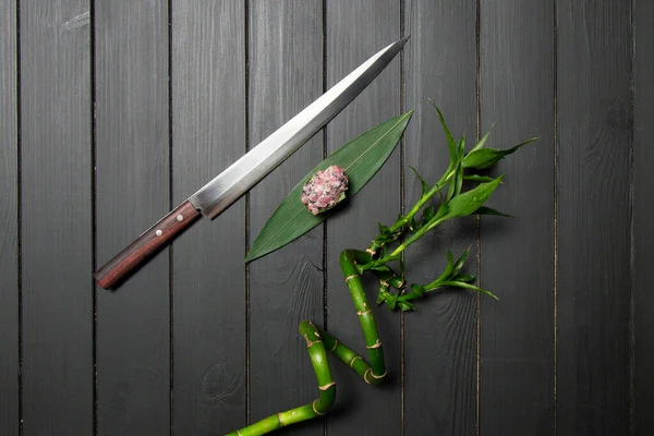 在日本菜刀和竹子植物附近的竹叶上 可以看到端着金枪鱼的贡干马古罗绿寿司和黄瓜中的黑鱼卵 泛亚餐厅餐 深色木板 — 图库照片