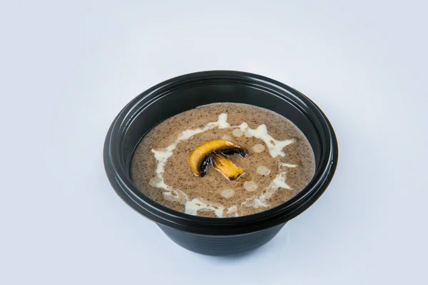 Mushroom cream soup with champignons and sour cream sauce served in plastic delivery bowl. Dish isolated on gray background. Vegetarian first dish in black plate. Vegan Food isolation — Stock Image Mushroom Cream Soup Champignons Sour Cream Sauce Served Plastic Delivery Royalty Free Stock Images
