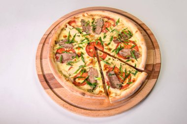 Kesilmemiş pizza, et, domates ve taze soğanlı soğanlı yeşil soğanlı arka planda izole edilmiş tahta kesme tahtası. Restoran fast food menüsü izolasyonu. Erimiş peynirli bir dilim et pizzası.