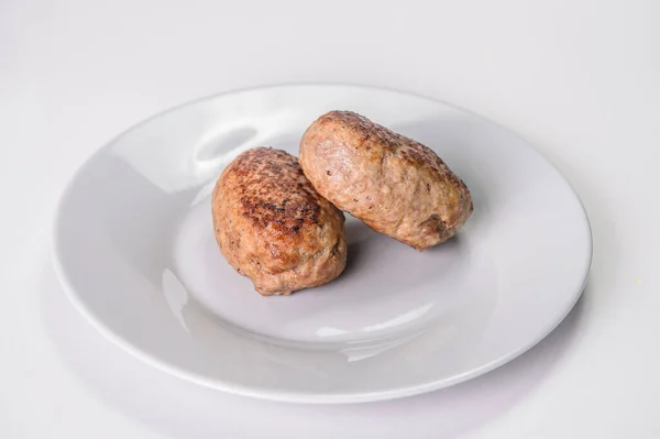 Gri tabakta servis edilen iki köfteye yakın çekim. Rus geleneksel ev yapımı et pirzolaları gri arka planda izole edilmiş. Slav yemek menüsü