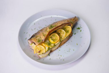 Limon dilimli fırında uskumru ve gri zemin üzerinde soğan. Taze dereotuyla servis edilen ızgara balık. Yiyecek izolasyonu 