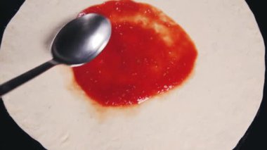 Pizzanın üzerine domates sosu konur. Şef pizza pişirir. Pizza pişirmek. Yemek videosu. Restoran veya kafeler için video. Pizza yapma süreci. Pizza bir İtalyan restoranının mutfağında hazırlanır. 