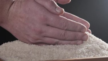 Birisi avuç içine beyaz pirinç alıyor ve geri dökmeye. Kuru pirinç hazırlanıyor. Japon mutfağı. Yavaş hareket. Kapat şunu. Yemek videosu. Pişirme pirinç.  