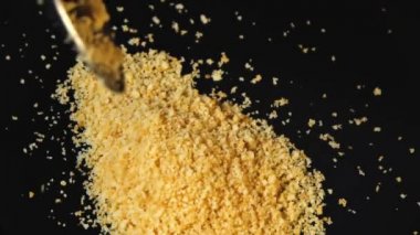 Birisi siyah bir arka planda ekmek kırıntıları döktüğü. Tatlı yapmak. Ekmek kırıntıları masaya düşüyor. Makro yavaş hareket üst görünümü yakın.  