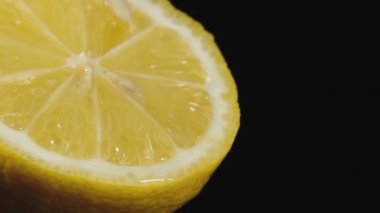 Su damlaları siyah bir arka planda kesilmiş kireç üzerine düşer. Su damlaları ile kesme Limes. Bir narenciye makro çekim. Bir arka planda su damlaları ışık yamalar. 