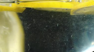 Limon dilimleri suya düşüyor. Suya düşen meyveler. Yavaş hareket siyah arka plan yakın çekim gıda video. Yavaş hareket su içine düşen limon dilimlenmiş.