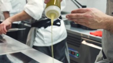 Birisi tavaya yağ döküyor. Şef sıcak tavaya zeytinyağı döküyor. Restoran mutfağı. Gıda video yavaş hareket yakın.