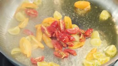 Domatesler tavada kızarıyor. Şef kiraz domatesi kızartıyor. Birisi kırmızı ve sarı domates yapıyor. Gıda video restoran mutfak kapatın.