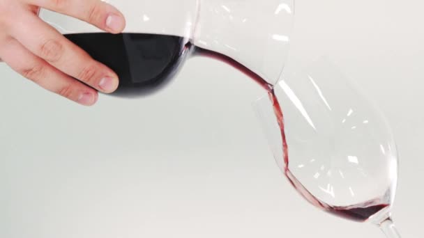 红酒正倒入玻璃杯中 有人正在把酒倒进玻璃杯里 在白色背景上浇注葡萄酒的近距离拍摄 — 图库视频影像