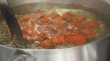 Çeri domatesler tencerede pişirilir. Restoranın mutfağında domatesler pişer. Kırmızı kiraz domatesleri pişer. Eller suya kiraz domates daldırma. Yemek videosunu kapatın