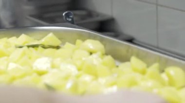 Çiğ patates. Patatesler tepside. Birisi patatesi yavaş çekimde atıyor.. 