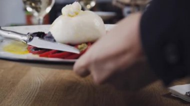 Domates ve fesleğenli burrata. Restoranın masasında güzel bir tabak ve bir bardak şarap duruyor. Restoranda servis edilen Burrata tabağı. Bir tabak şarapla güzel bir kompozisyon..