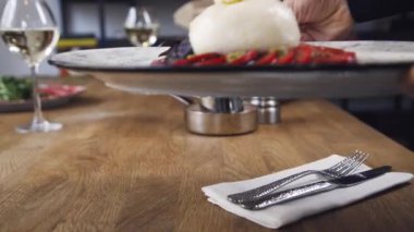 Domates ve fesleğenli burrata. Restoranın masasında güzel bir tabak ve bir bardak şarap duruyor. Restoranda servis edilen Burrata tabağı. Bir tabak şarapla güzel bir kompozisyon..