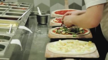 Şef restoranda pizza pişiriyor. Pizza yapma süreci. Birisi mutfakta etli pizza hazırlıyor..