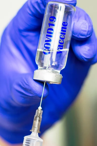 파란 의료용 장갑을 끼고 한 손으로 주사기에 새겨진 COVID19 백신 과 함께 한 암 푸 울에서 백신을 집어 든다. — 스톡 사진