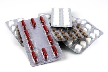 Beyaz arka planda su toplayan farklı haplardan oluşan bir yığın.