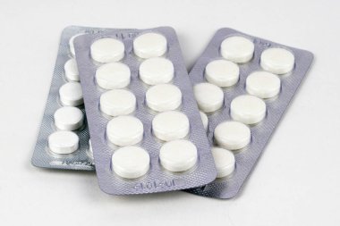 Beyaz arka planda su toplayan üç paket beyaz tablet.