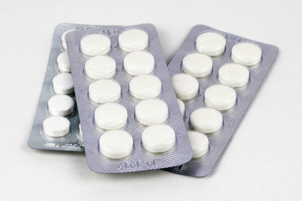 three packs of white tablets in blisters on a white background