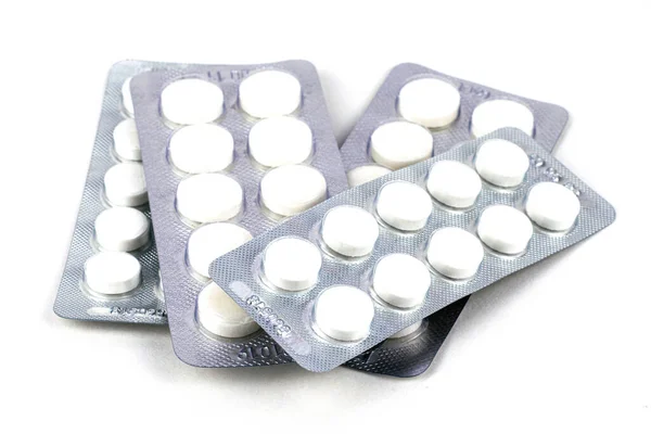 Beyaz arka planda kabarcıklar içinde dört paket beyaz tablet.
