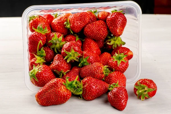 Overturned Transparent Plastic Container Red Ripe Juicy Strawberries Scattered Table — Stock Photo, Image