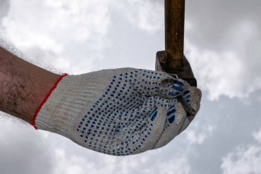 Bir eldiven içindeki bir el çivi tutar. Bir çekiç aşağı çekiçle çekilir.